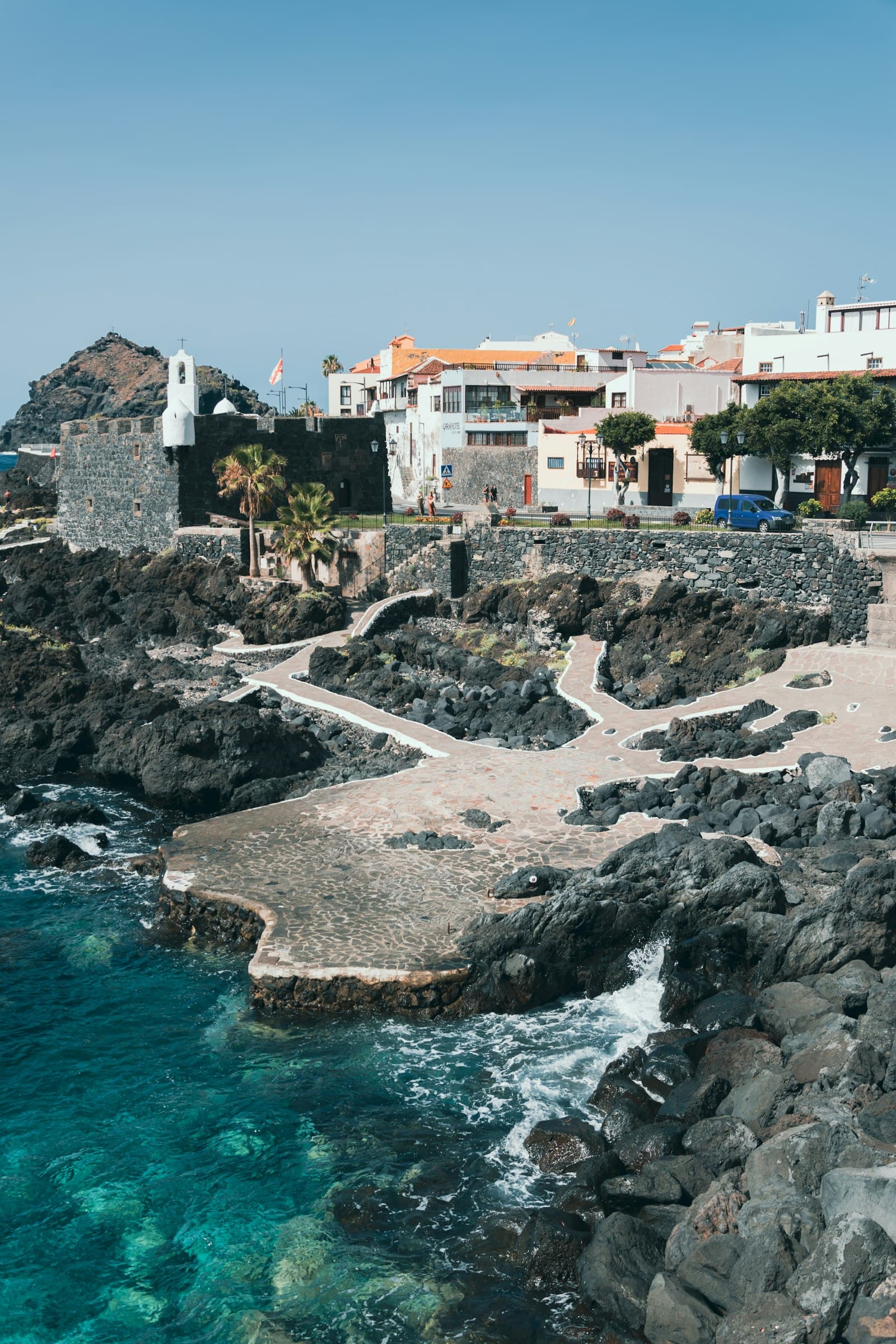A rocky Canary shoreline with white houses set back behind it.