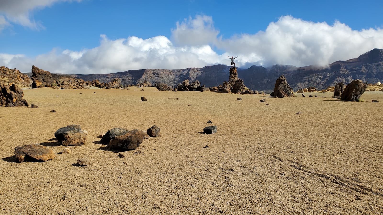 A rocky, sparsely vegetated volcanic landscape under open sky.