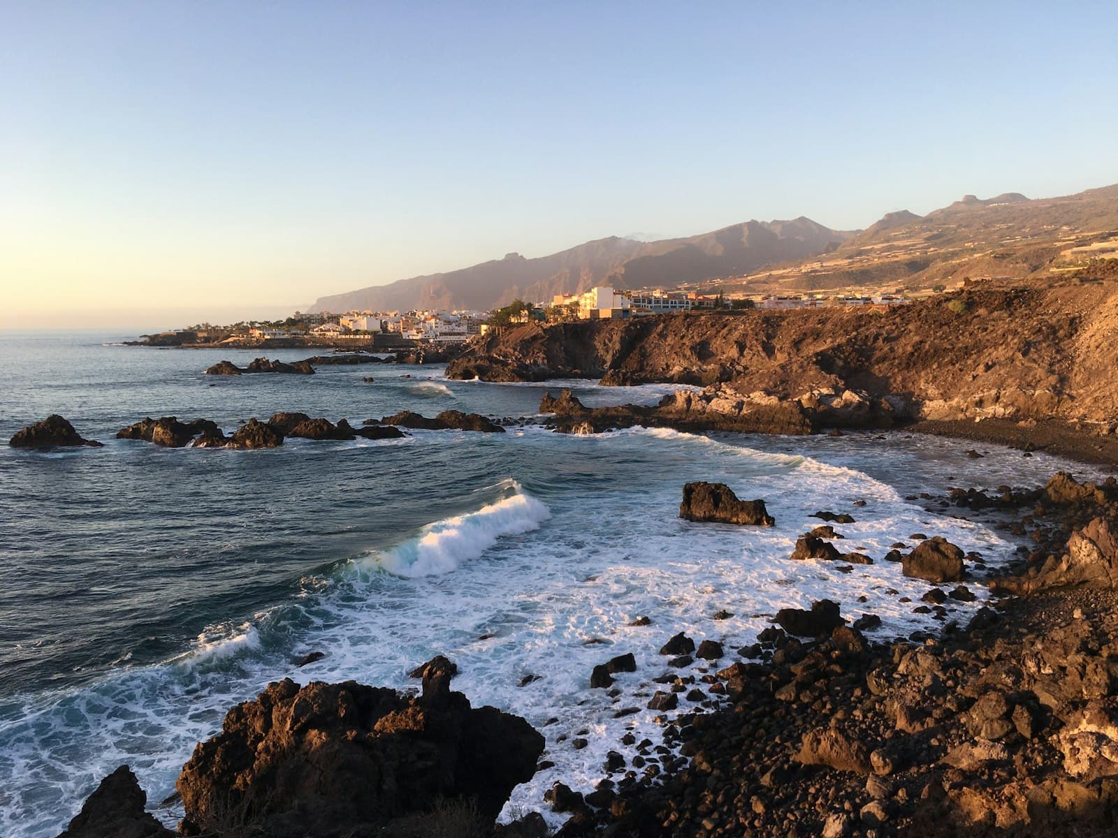 Waves breaking over a dark volcanic rock shelf on the Canary coast.